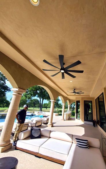 A man standing on a porch with a ceiling fan