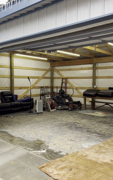 A garage with a couch and a lawn mower in it.