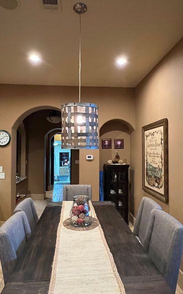 A dining room with a table and chairs and a lamp hanging from the ceiling.