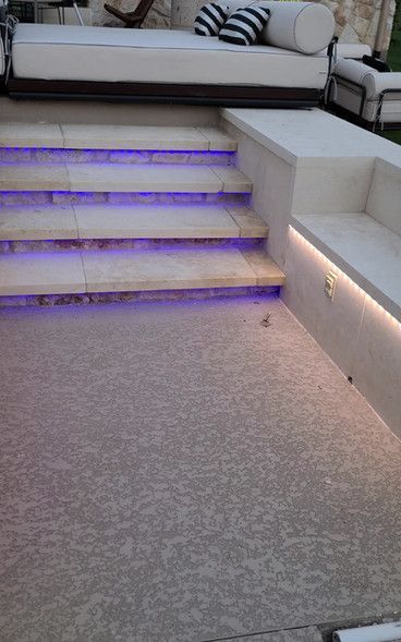 A couch is sitting on top of a set of stairs with purple lights.