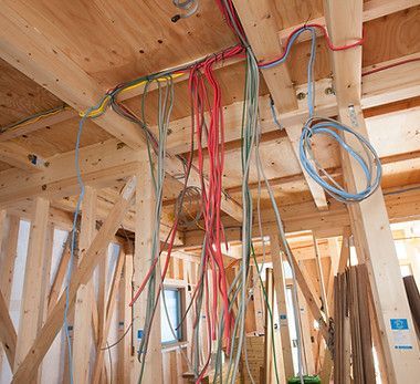 A bunch of wires are hanging from the ceiling of a building under construction.