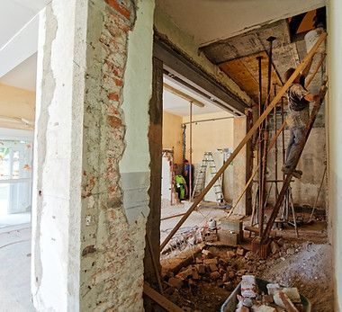 A man is standing on a ladder in a room under construction.