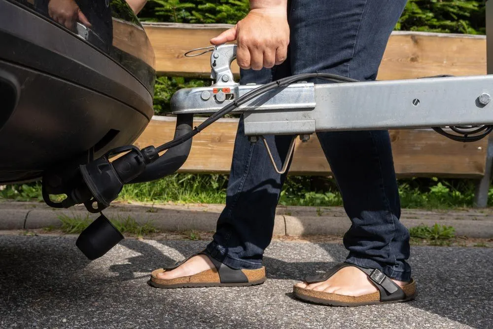 A Person is Attaching a Trailer to the Back of a Car — Truck Training and Assessments In Umina Beach, NSW