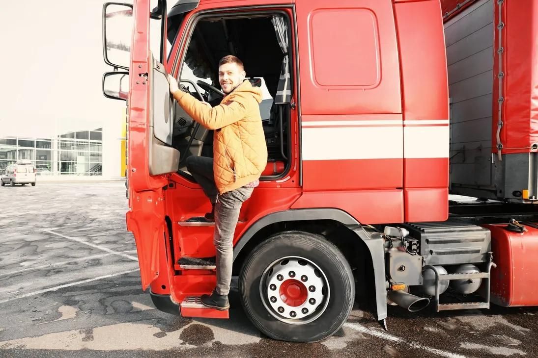 A Man is Getting Out of a Red Semi Truck — Truck Training and Assessments In Umina Beach, NSW