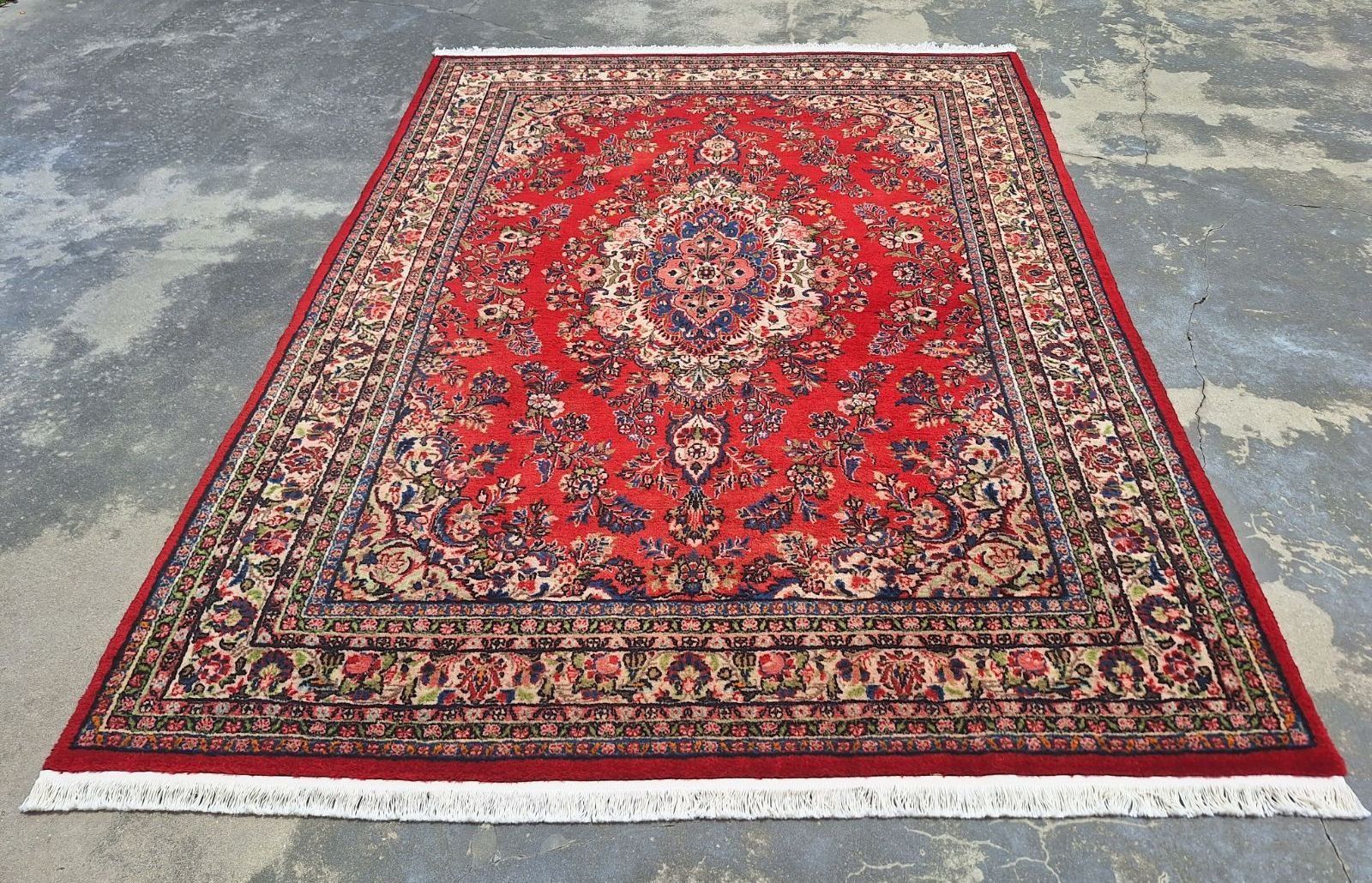 A large red rug is sitting on a concrete surface.