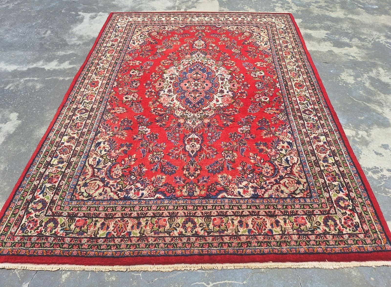 A large red rug is sitting on a concrete surface.