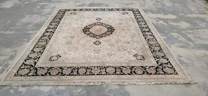 A large rug is sitting on a concrete floor.