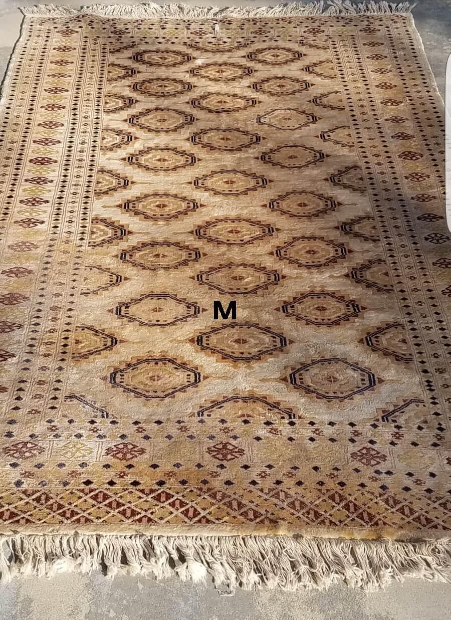 A rug with fringe is sitting on a concrete floor.