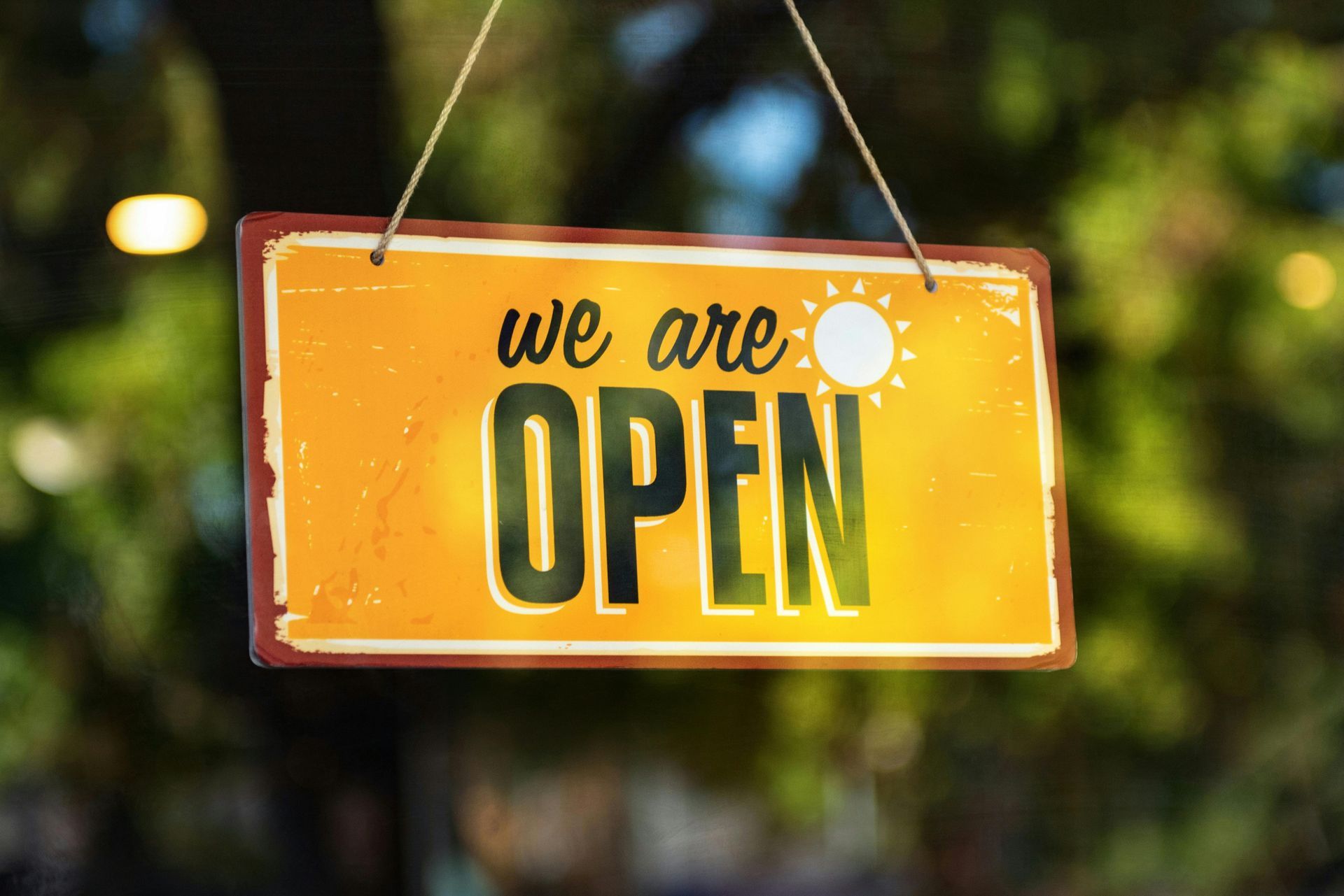 A yellow sign that says `` we are open '' hangs from a rope.