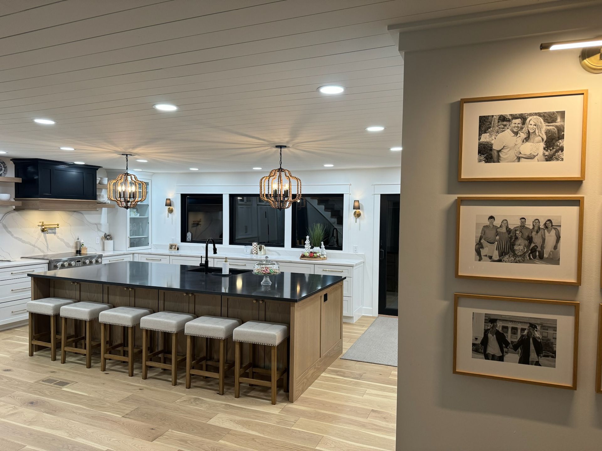 A kitchen with a large island and stools and pictures on the wall
