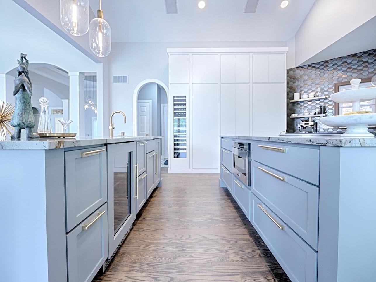 A kitchen with blue cabinets , stainless steel appliances , and marble counter tops.