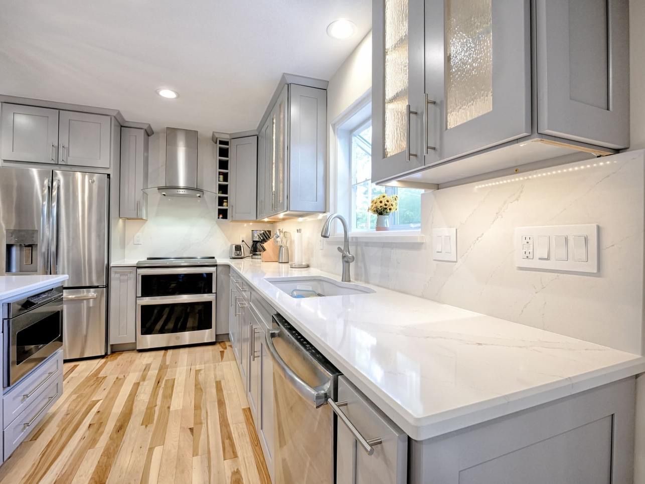 A kitchen with white cabinets , stainless steel appliances , and hardwood floors.