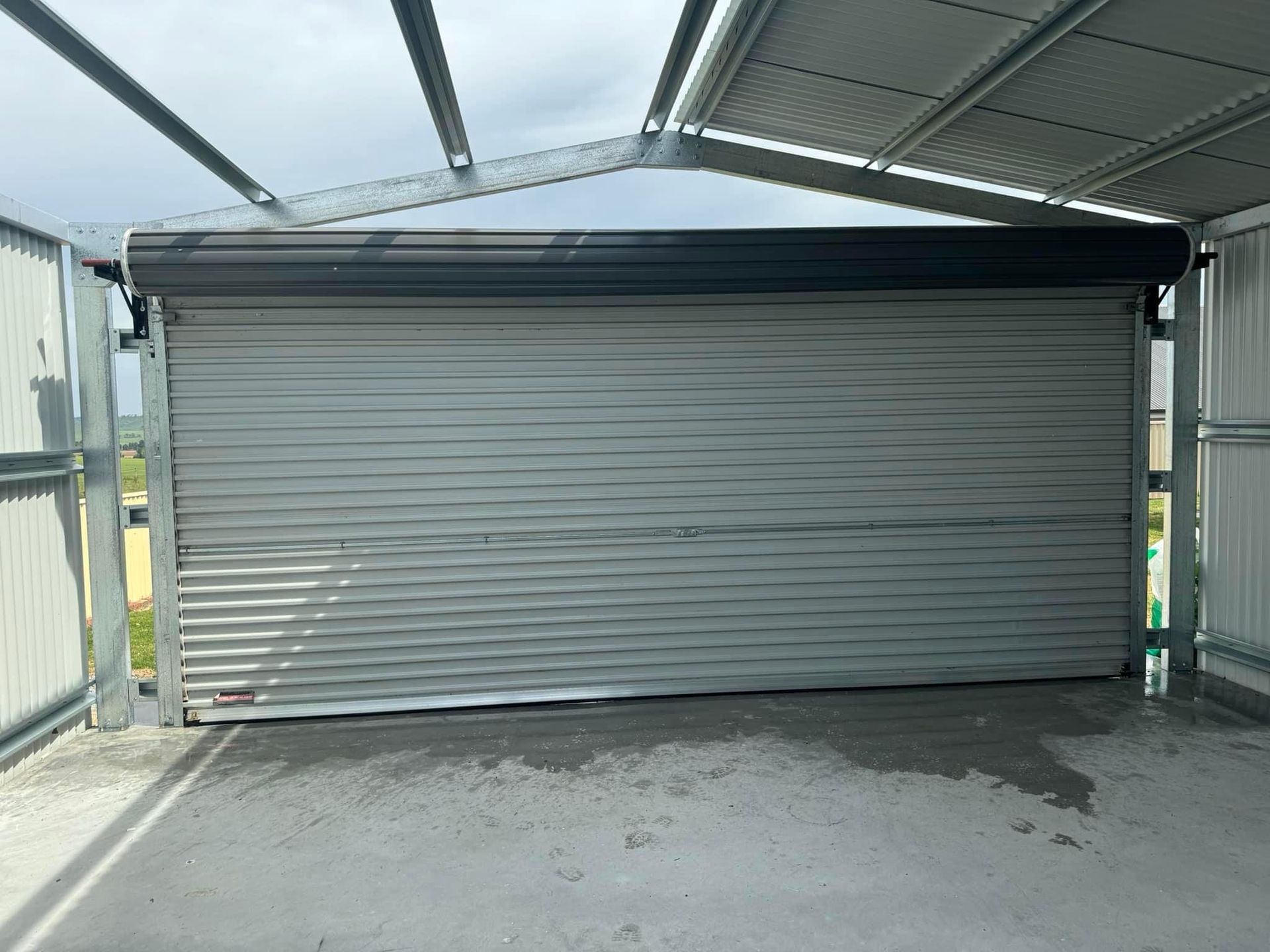 A white garage door is open in a parking lot.