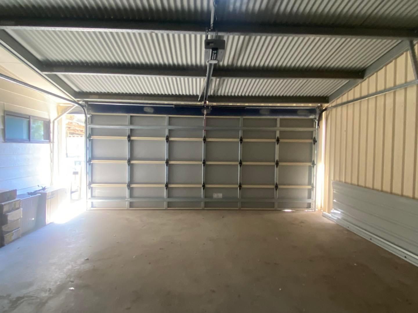 An empty garage with a large garage door open.