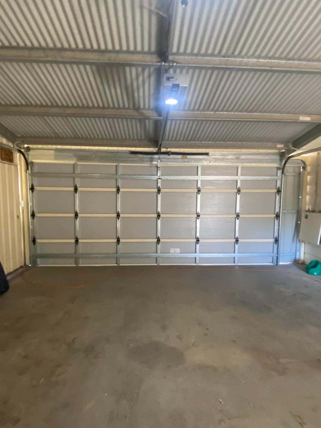 An empty garage with a large garage door and a ceiling fan.
