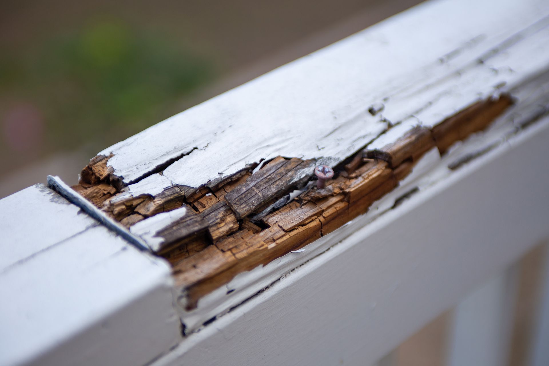 A close up of a wooden railing with peeling paint.