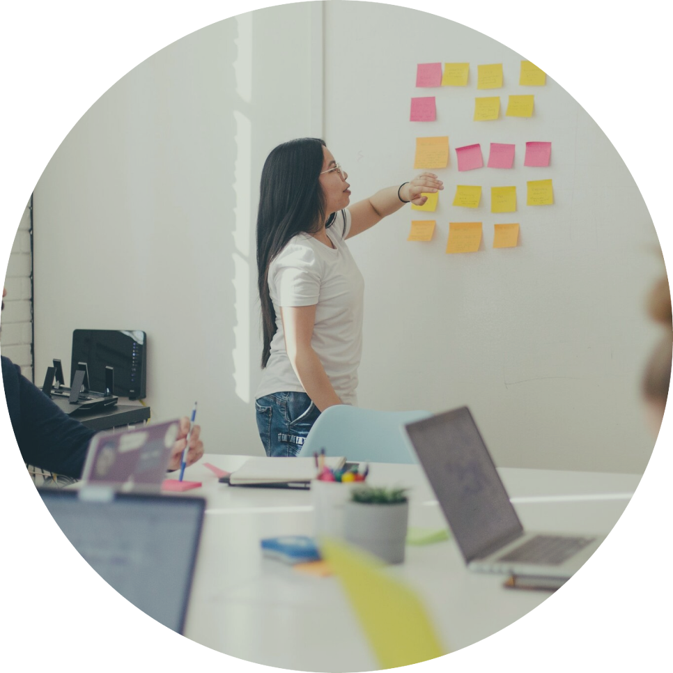 A woman is standing in front of a wall with sticky notes on it.
