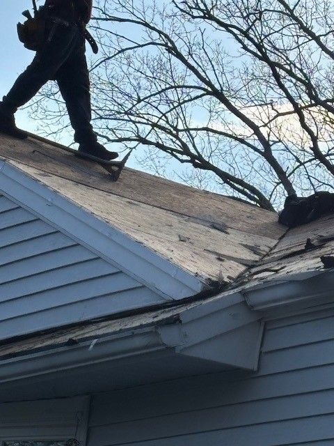 Affordable Roofing Services roofer removing old shingles from white-sided home
