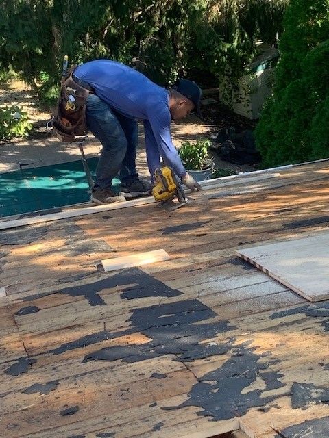 Affordable Roofing Services roofer cutting wooden roof with saw on sunny day