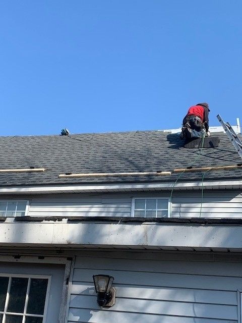 Roofer on gray shingle roof, installing shingles in ocean city, new jersey