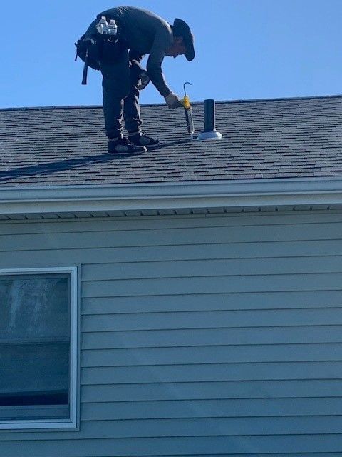 Affordable Roofing Services roofer inspecting roof vent on blue siding home in vineland, new jersey