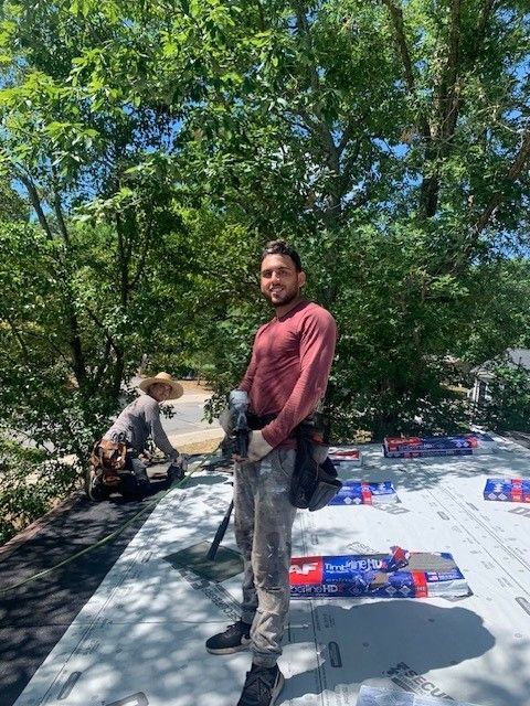 Two affordable roofing services roofers on top of roof installing shingles, one with tool