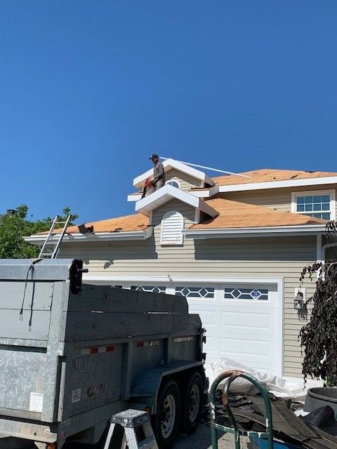 Affordable Roofing Services employee replacing shingles on residential roof with trailer and ladder in Mays Landing, NJ