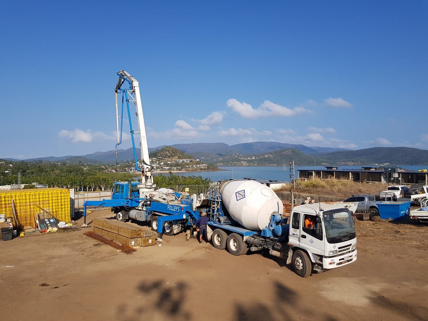 A Concrete Mixer Truck is Driving Down a Dirt Road — Polley's Concrete Pumping in Sarina, QLD