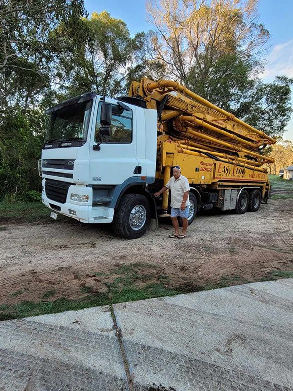 A Man is Standing in Front of a Concrete Pump Truck — Polley's Concrete Pumping in Kuttabul, QLD