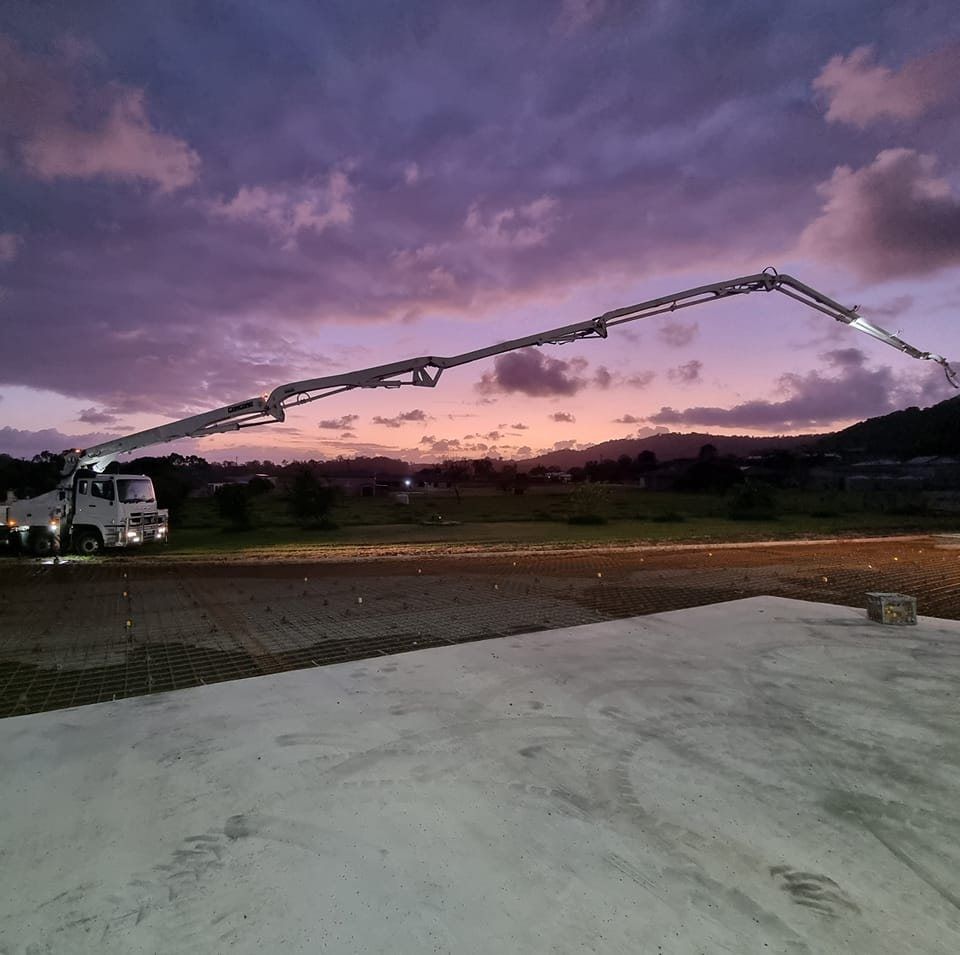 A White Truck With a Long Arm is Parked in a Parking Lot at Sunset — Polley's Concrete Pumping in Kuttabul, QLD