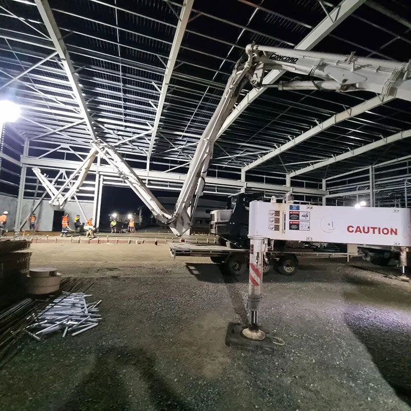 A Concrete Pump is Being Used to Pump Concrete Into a Building at Night — Polley's Concrete Pumping in Kuttabul, QLD