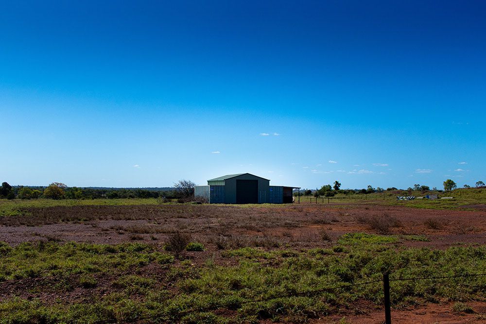 A Large Building in the Middle of a Field With a Blue Sky in the Background — Polley's Concrete Pumping in Moranbah, QLD