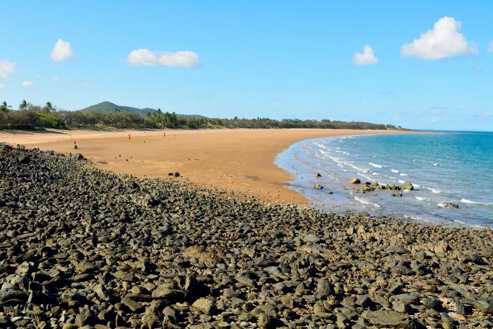 A Rocky Beach With a Large Body of Water in the Background — Polley's Concrete Pumping in Sarina, QLD
