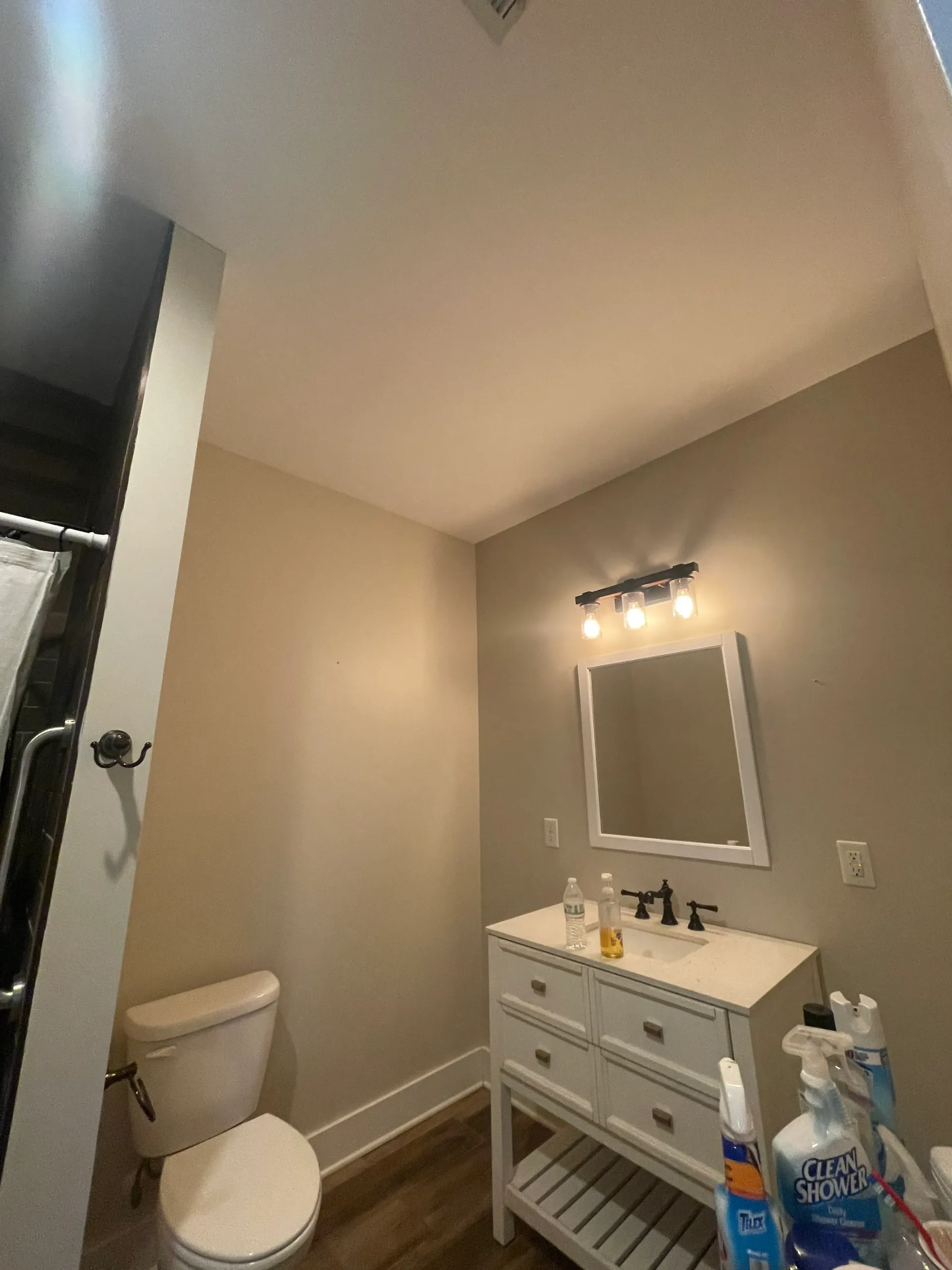 A bathroom with a toilet , sink and mirror.