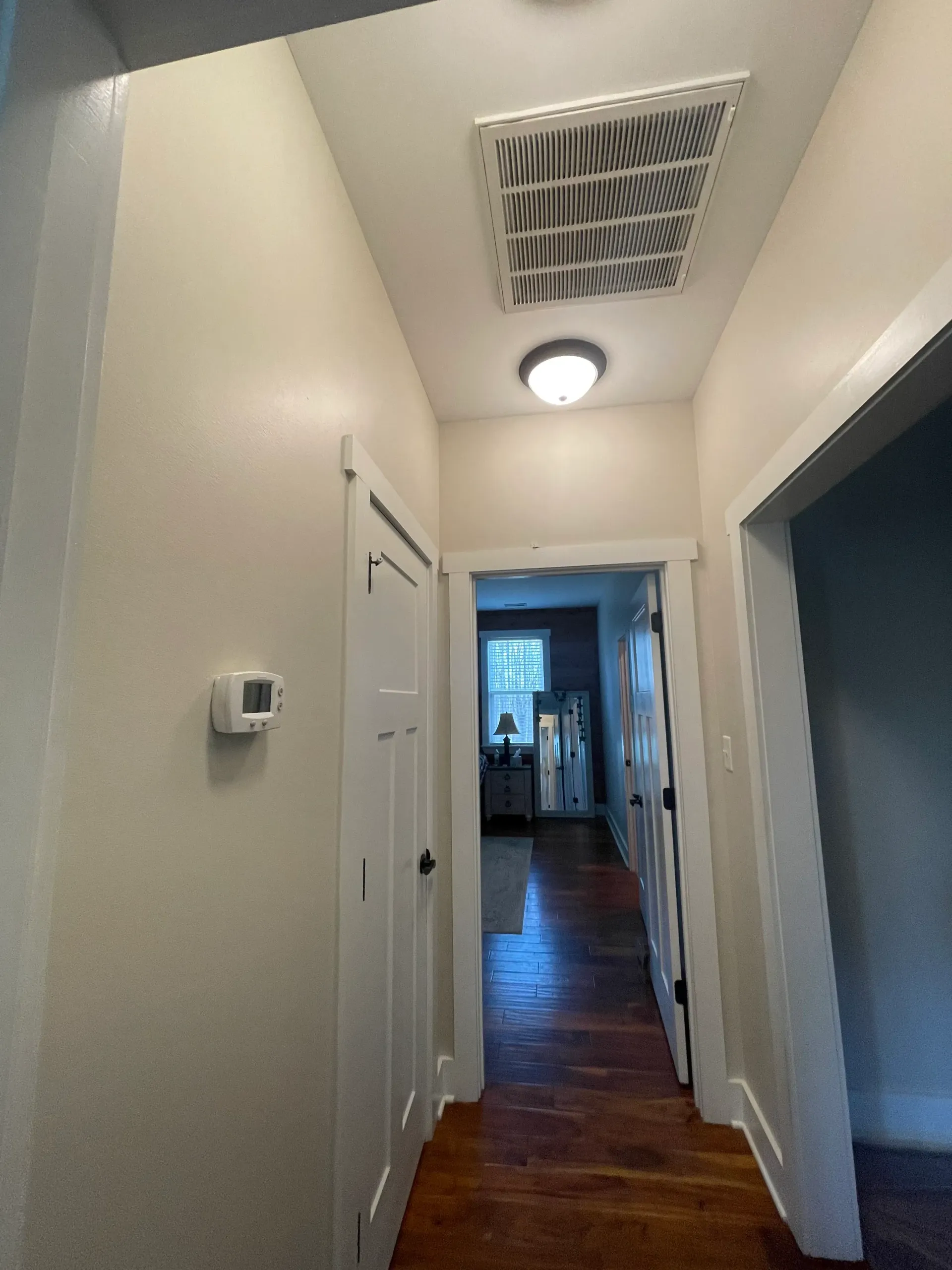 A hallway in a house with a ceiling fan and a light.