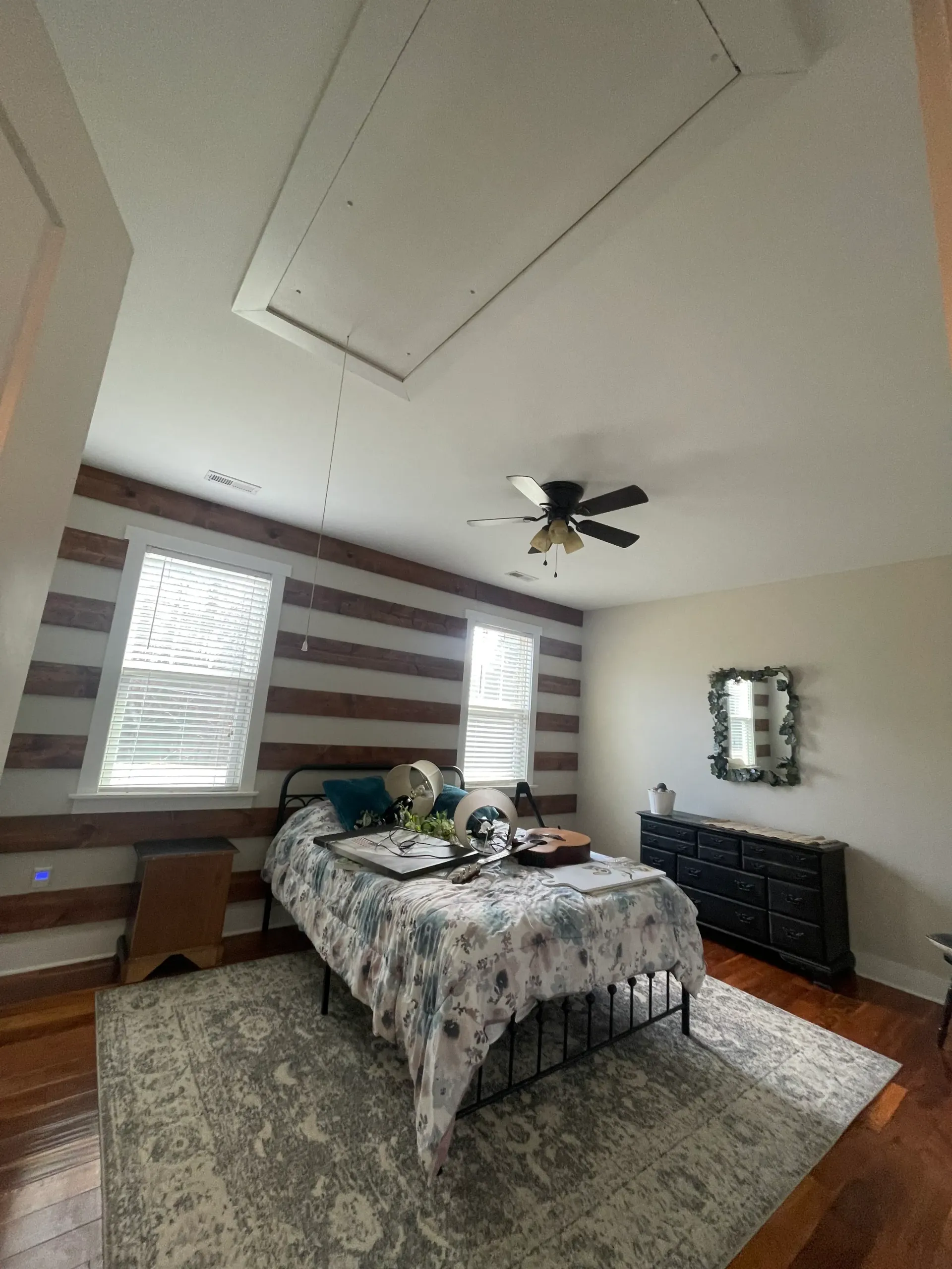 A bedroom with a bed , dresser , and ceiling fan.