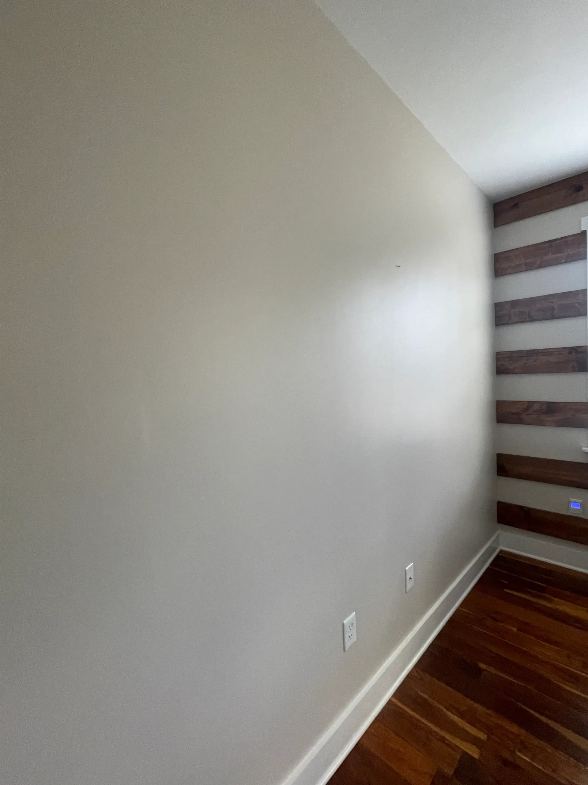 A room with a wooden floor and a striped wall.