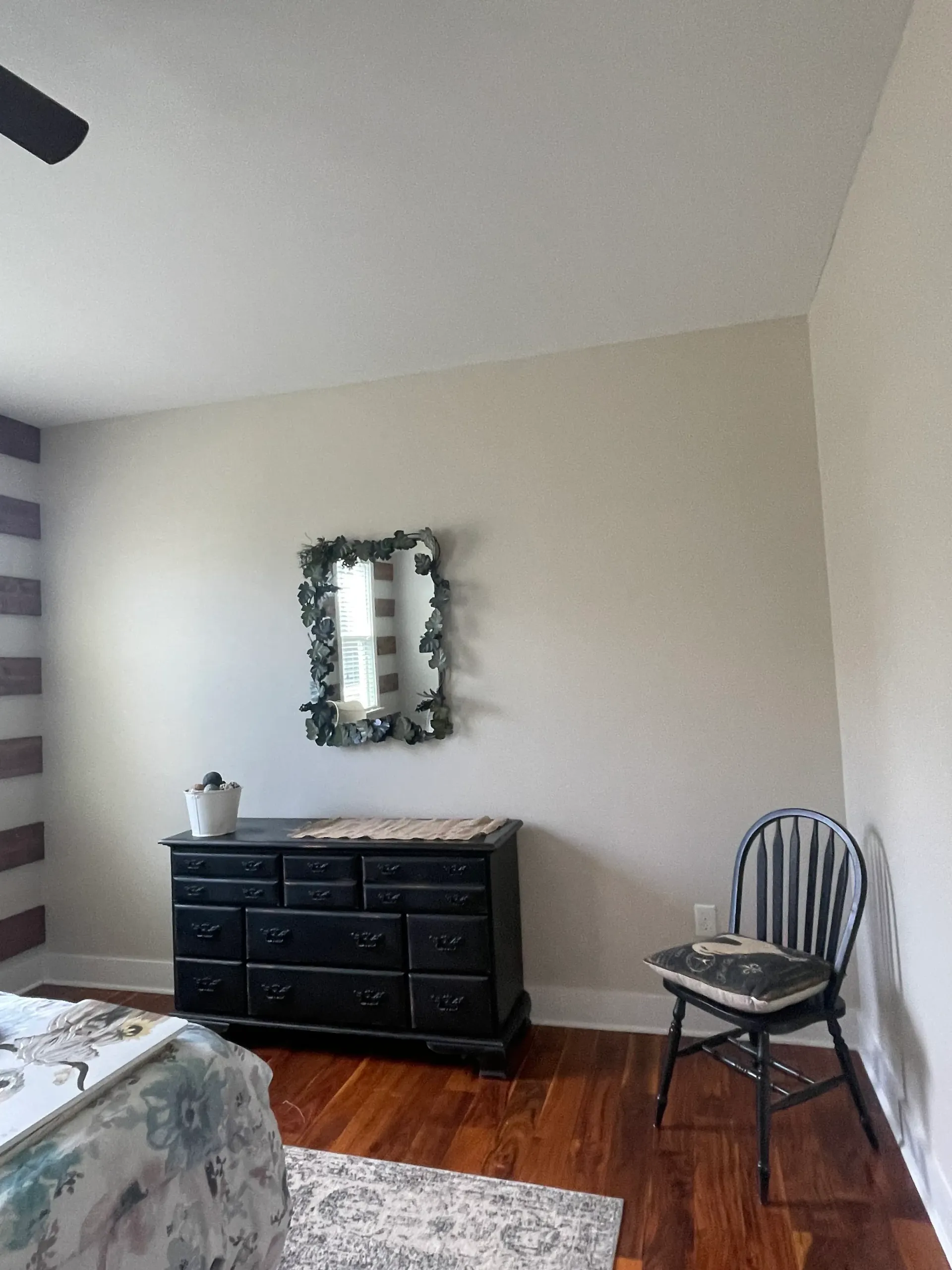 A bedroom with a dresser , chair , and mirror on the wall.