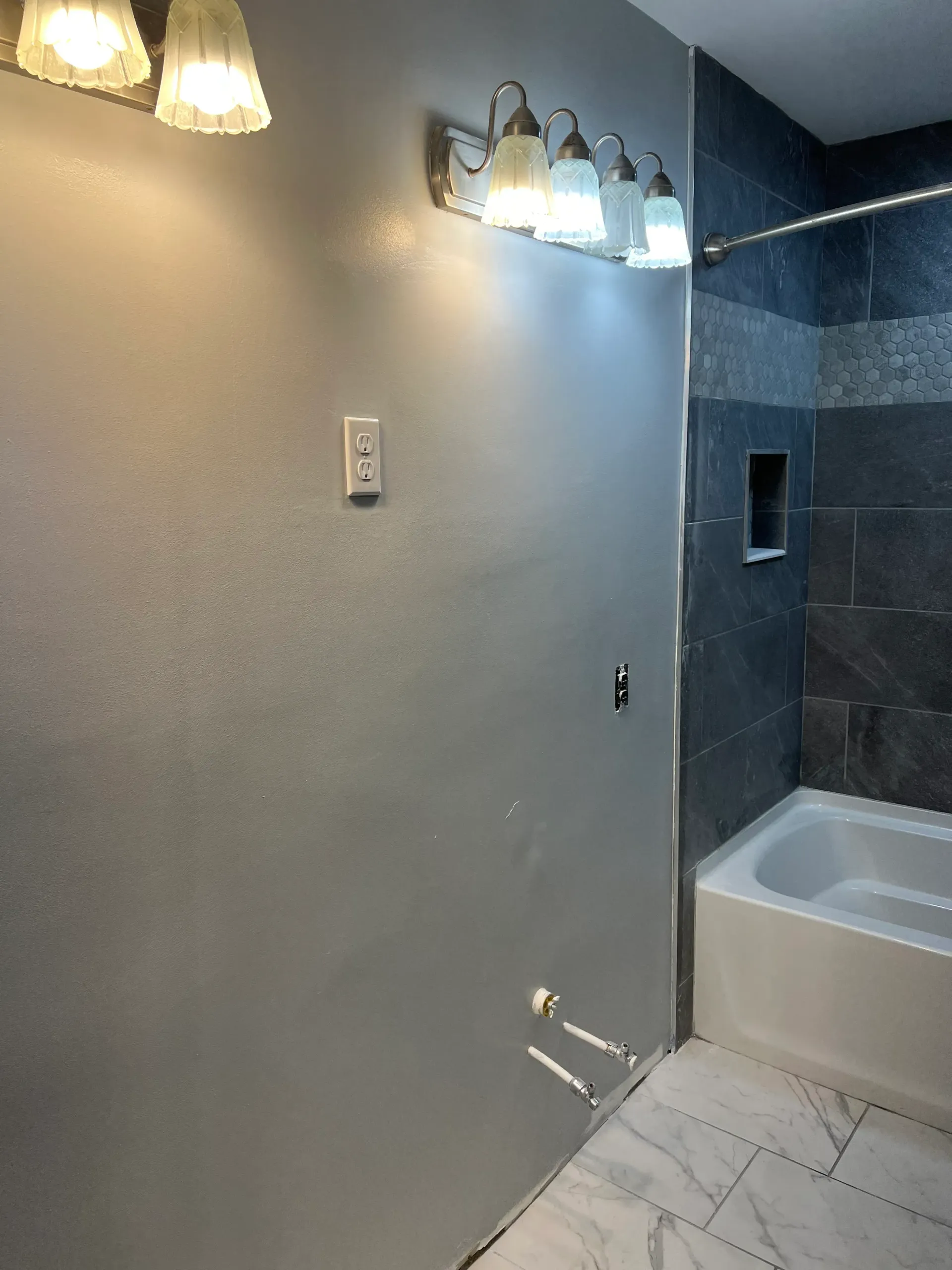A bathroom with a bathtub and a light fixture on the wall.