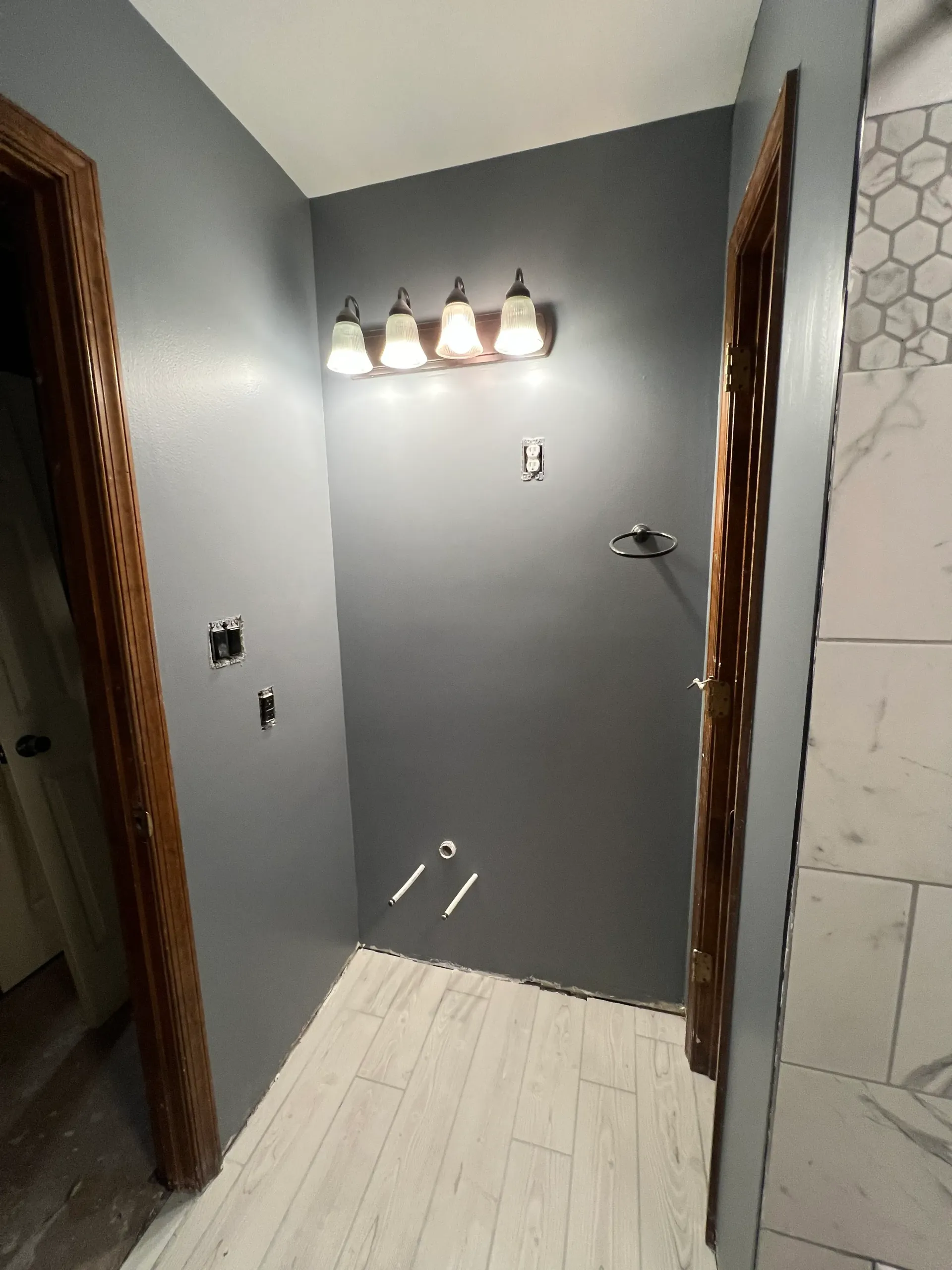 A bathroom with a shower and a light fixture on the wall.