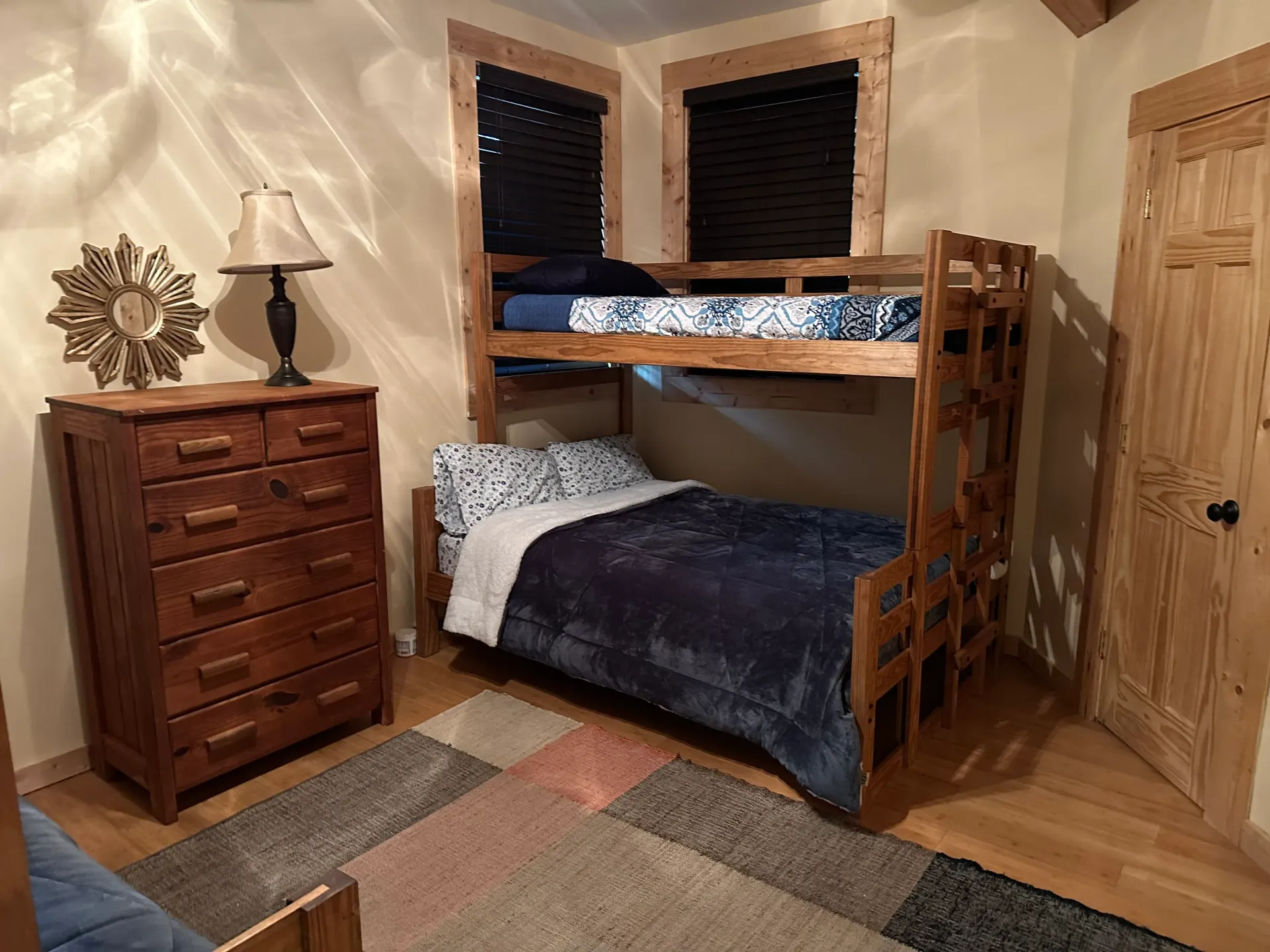 A bedroom with a bunk bed , dresser , and lamp.