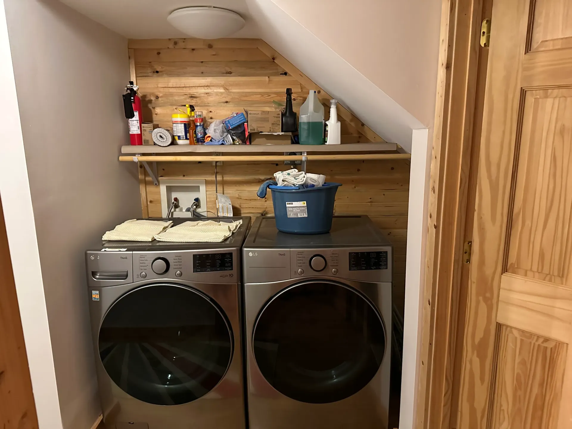 A washer and dryer are in a laundry room under a staircase.