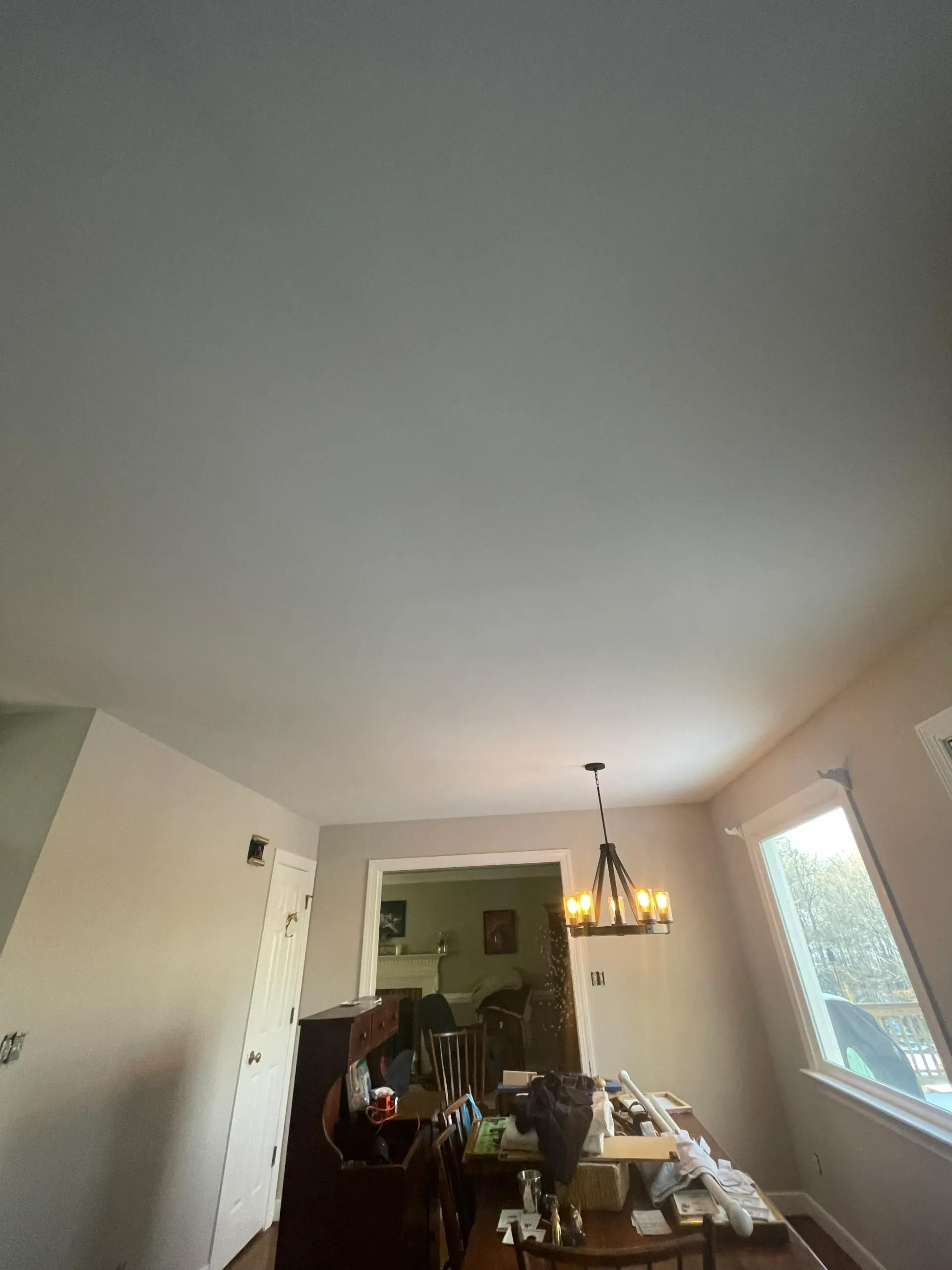 A dining room with a white ceiling and a chandelier hanging from the ceiling.