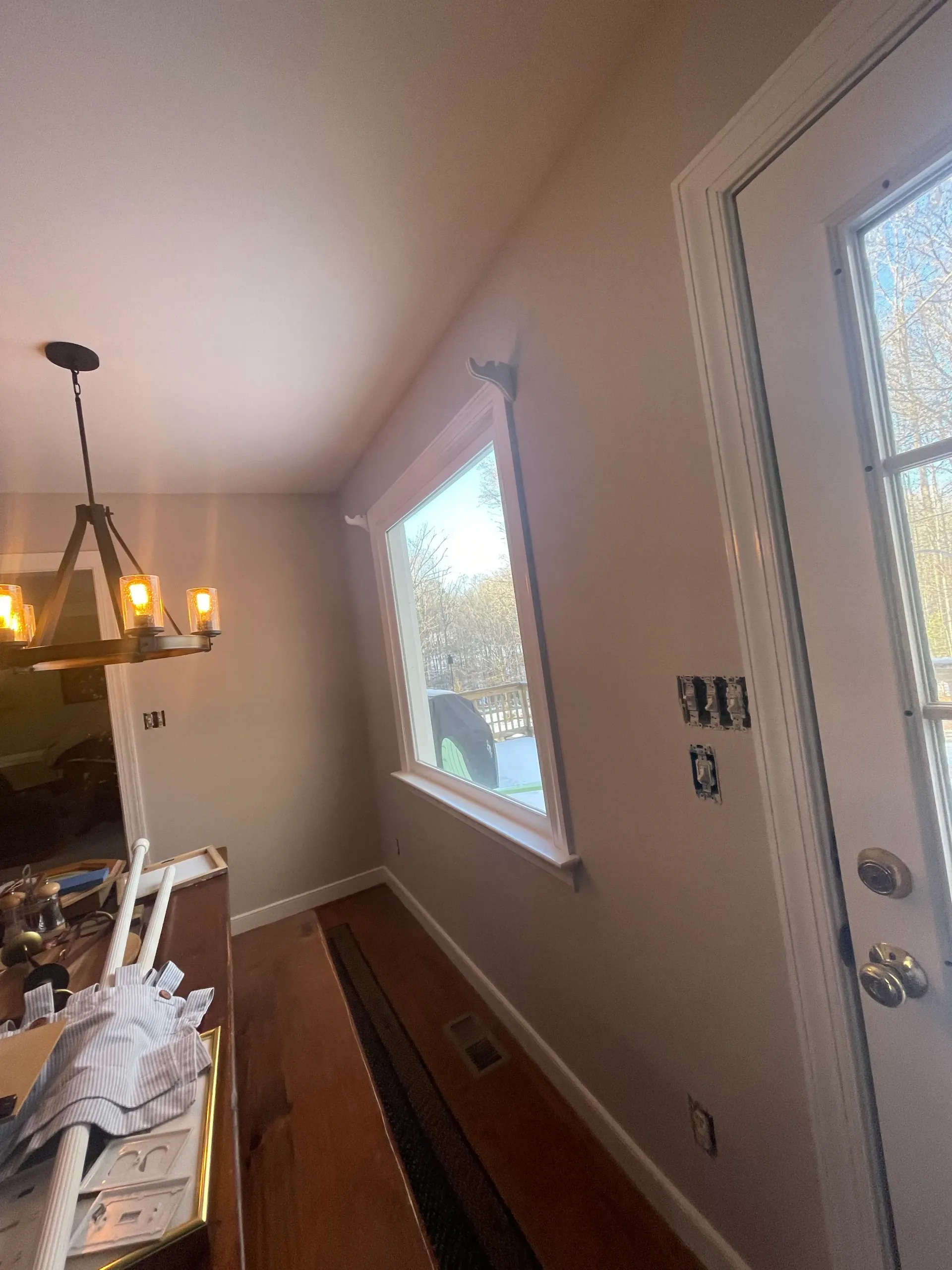 A room with a chandelier hanging from the ceiling and a window.