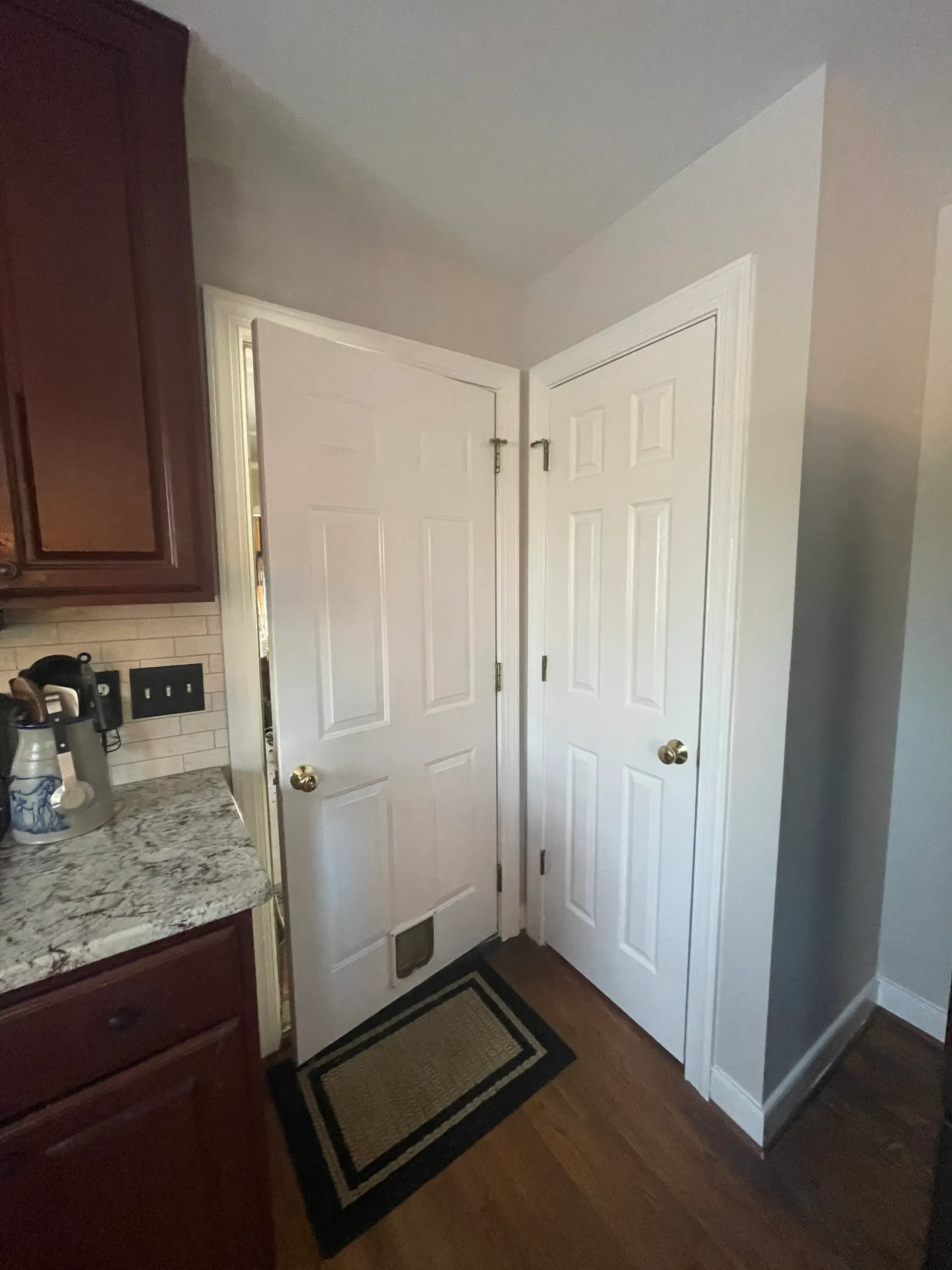 A kitchen with a cat door in the corner