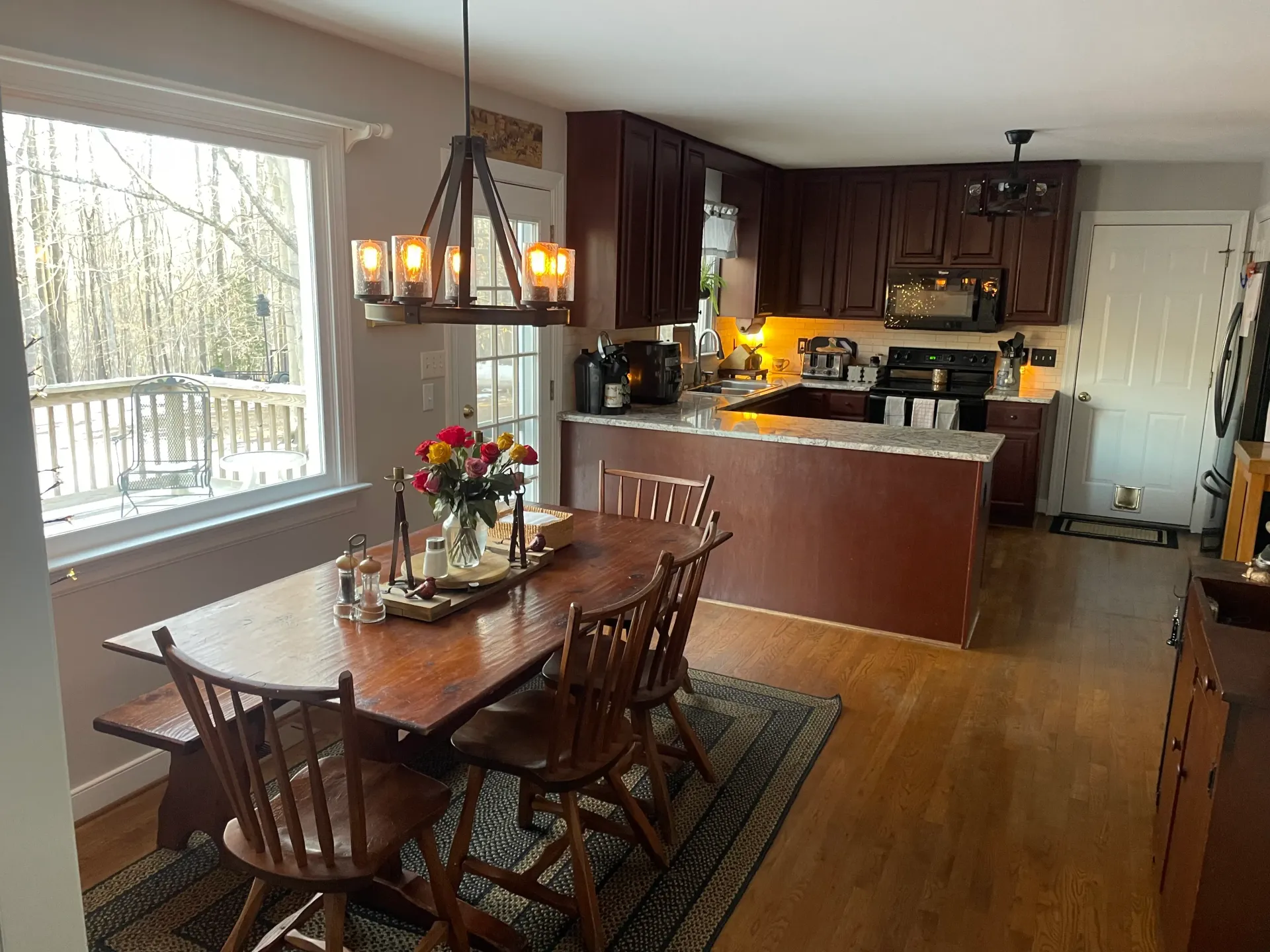 A dining room table and chairs in a kitchen with a chandelier hanging from the ceiling.