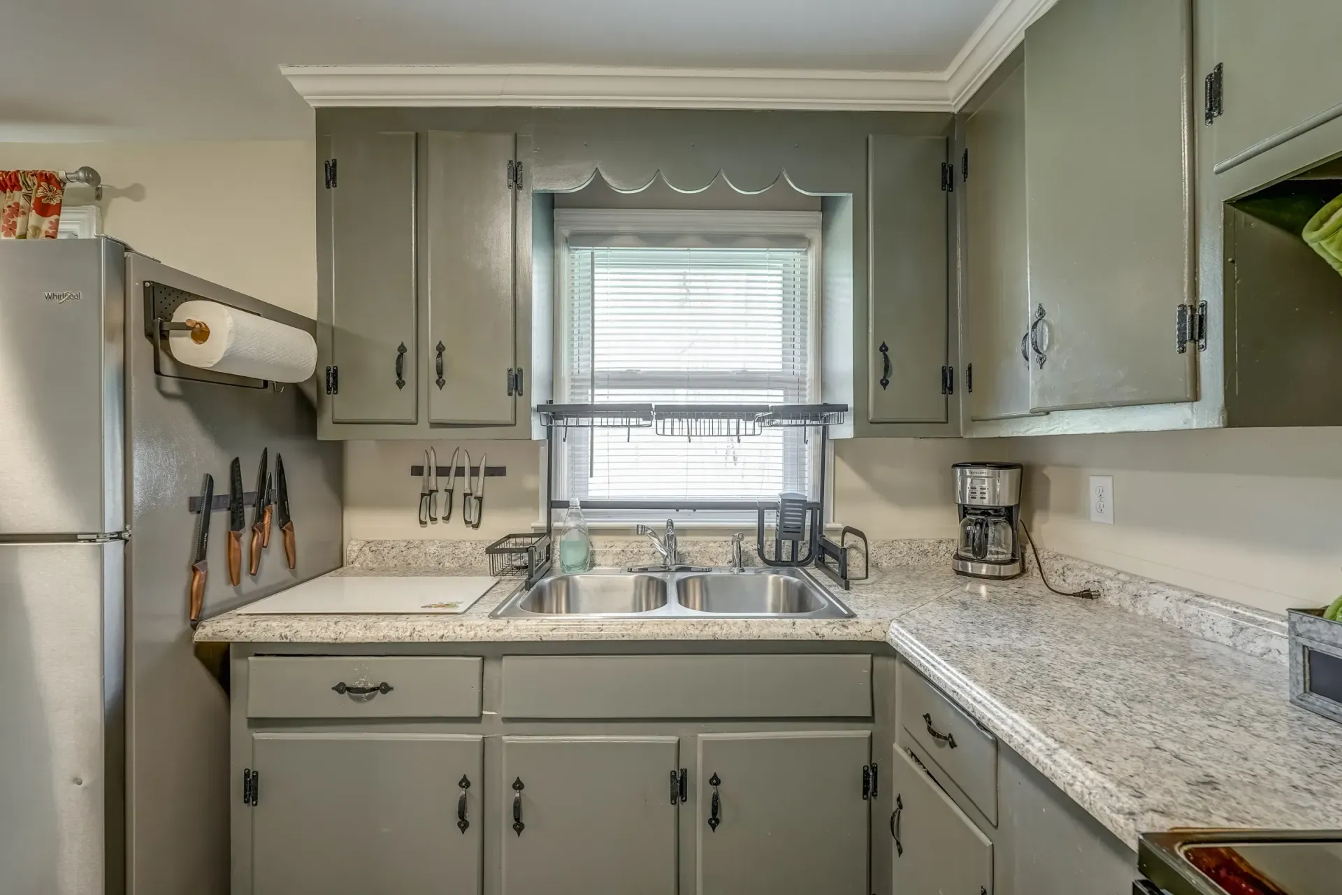 A kitchen with two sinks , a refrigerator , and a window.