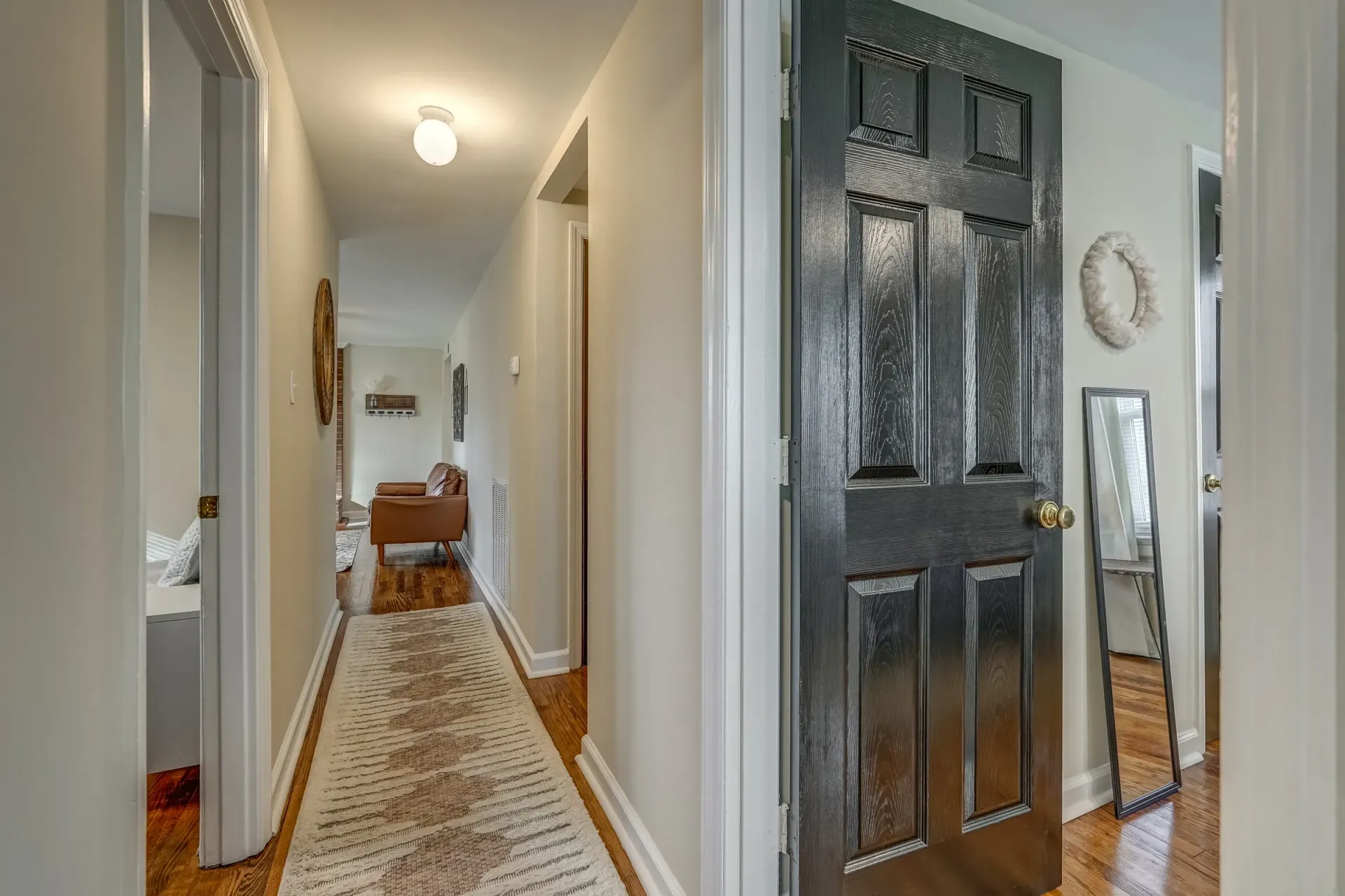 A hallway with a black door and a rug.