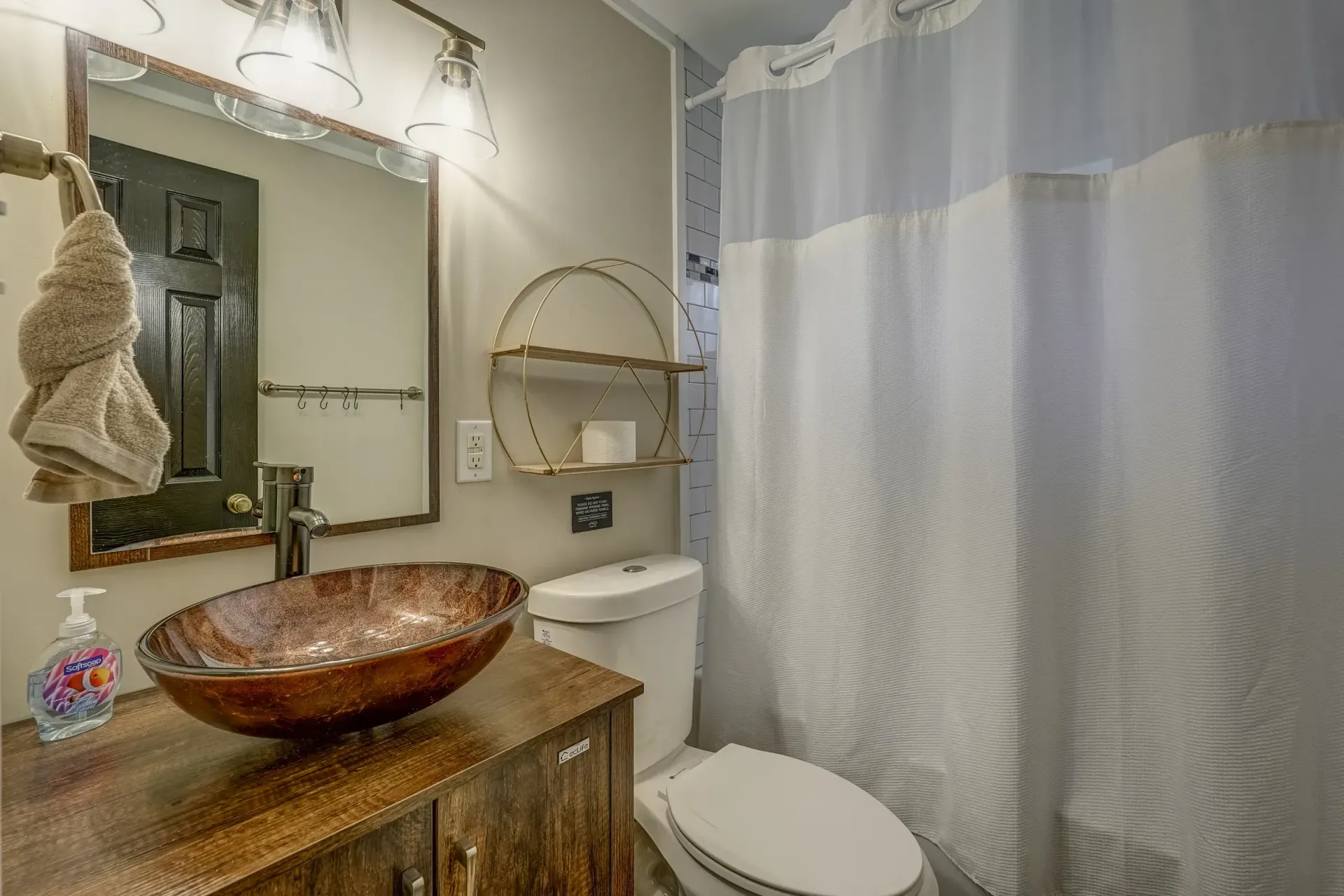 A bathroom with a sink , toilet , mirror and shower curtain.