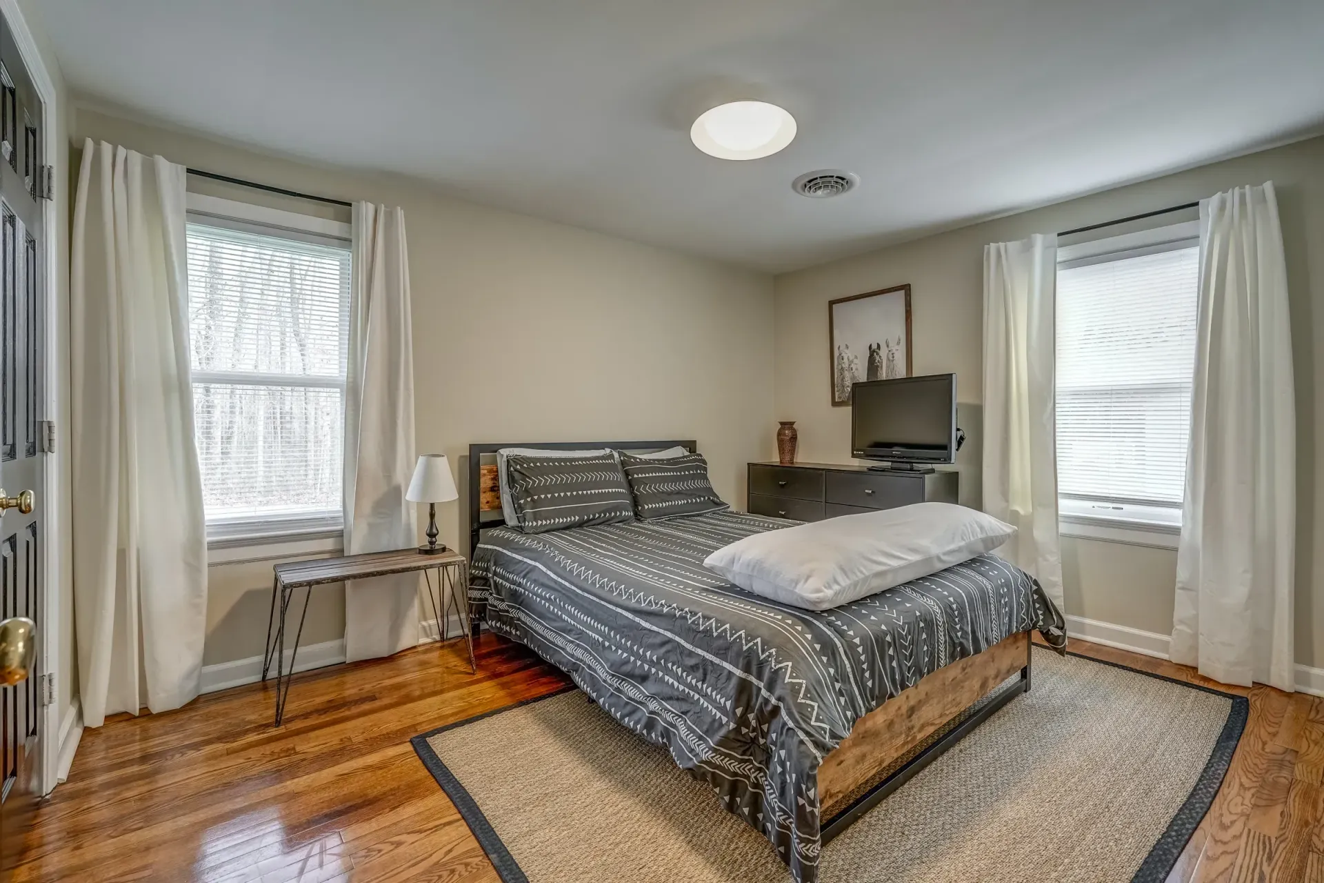 A bedroom with a bed , rug , window and television.